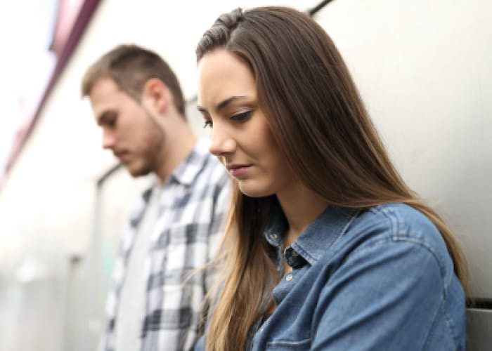 sad couple or friends complaining in the street