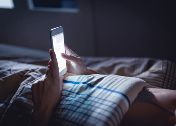 woman using phone late at night in bed