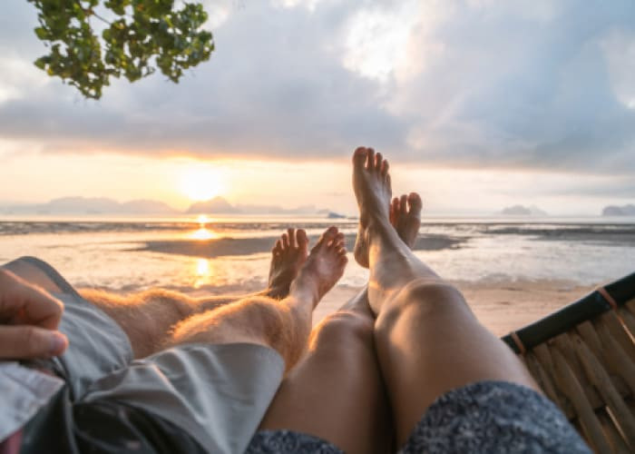 personal perspective of couple relaxing on hammock feet view