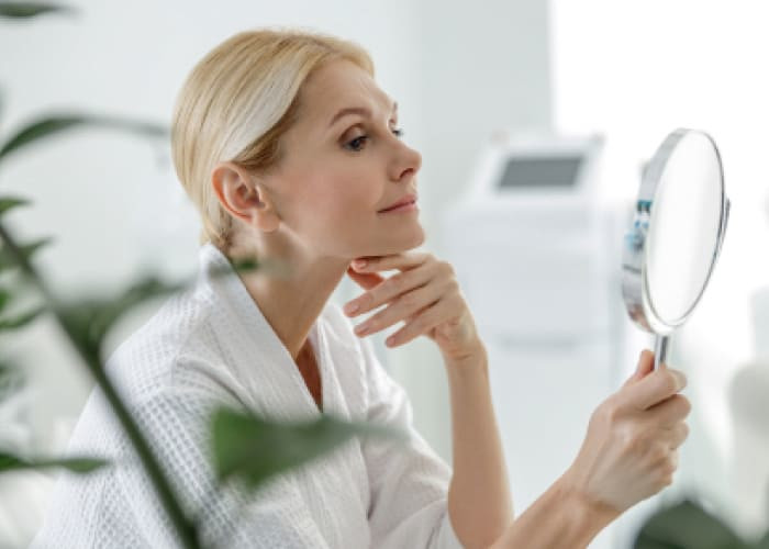 smiling pretty mature woman using mirror