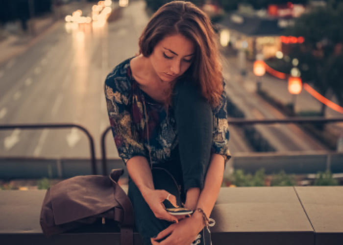 depressed teenage girl texting on the bridge