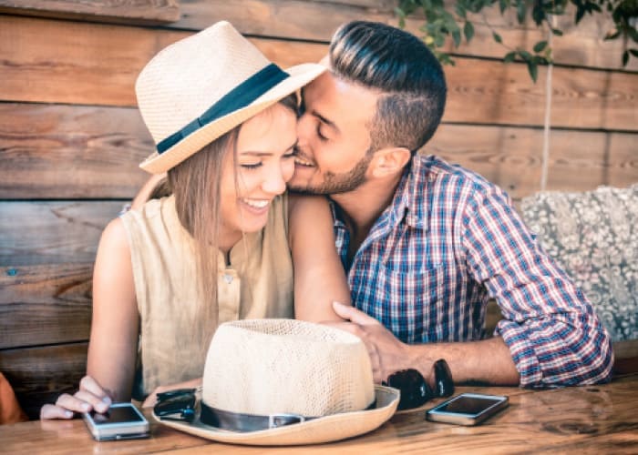 man whispering in lady's ear