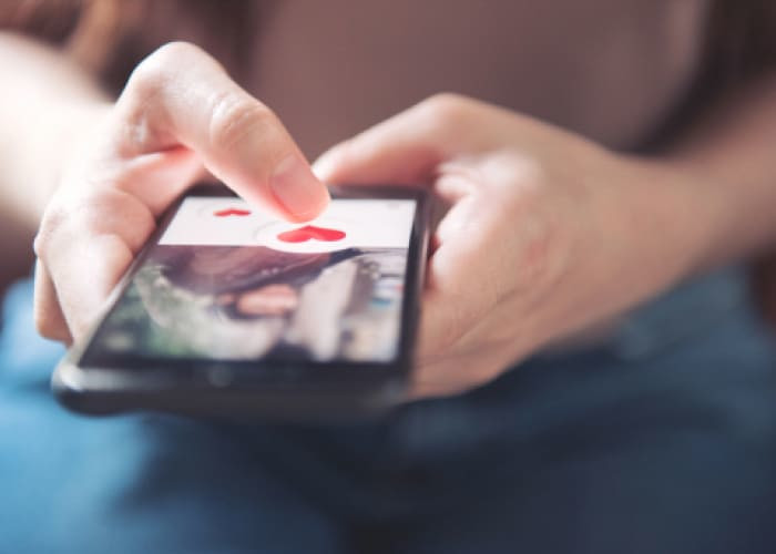 woman pushing hear icon on phone screen