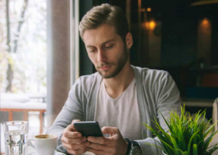 man in a café looking at a phone