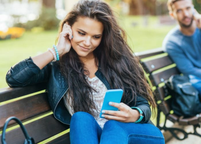 girl texting on cell phone while a guy talking on the phone