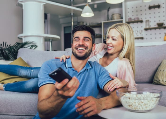 young couple watching tv on a sofa at home