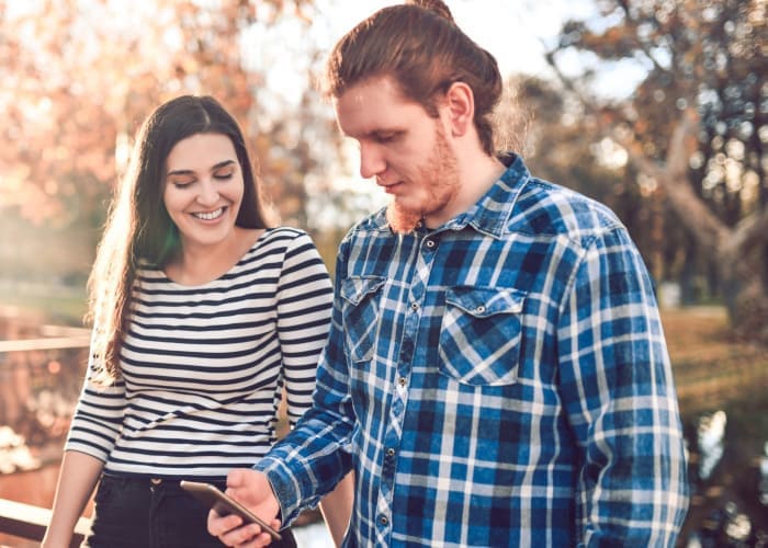 mixed couple searching for other location to visit in park on map		