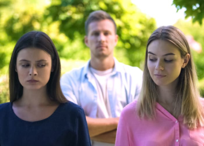 two jealousy women looking each other man on background love triangle conflict