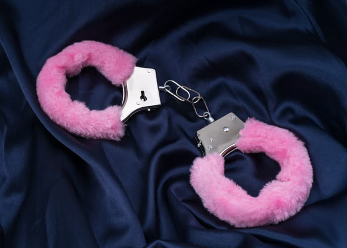 sex handcuffs with pink fur on blue silk bedding concept role playing games			