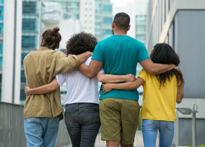 close male and female friends walking down city street	