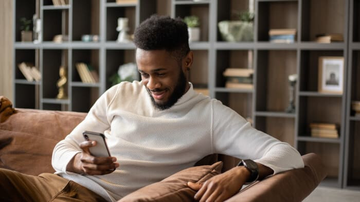 smiling young black man having video call at home